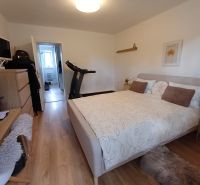 Schlafzimmer in einer 2-Zimmer-Wohnung mit Holzboden und Fitnessgerät.