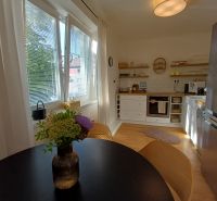 Küche in einer 2-Zimmer-Wohnung mit Holzboden, Fenstern und einem Tisch mit Blumen.