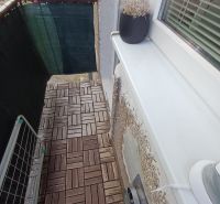 Balkon in einer 2-Zimmer-Wohnung mit Holzboden und einem Blumentopf.