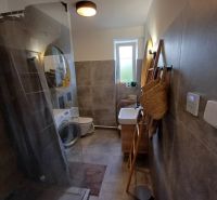 Badezimmer mit Waschmaschine und Duschkabine in einer 2-Zimmer-Wohnung.