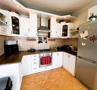 Küche in einem Einfamilienhaus mit weißen Schränken und einem Kühlschrank aus Edelstahl.