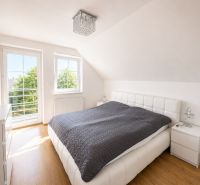 Schlafzimmer im Einfamilienhaus mit großem Fenster und Boden in Holzoptik.