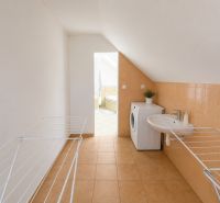 Waschküche in einem Einfamilienhaus mit Waschmaschine, Waschbecken und Wäscheständer.