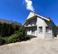 Ein Einfamilienhaus in Šamorín mit einem gepflegten Garten und einer Betonzufahrt.