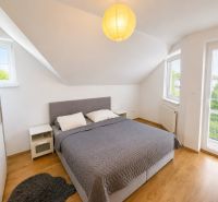 Schlafzimmer mit Dachfenstern, grauem Bett und Holzboden in einem Einfamilienhaus.