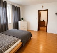 Schlafzimmer im Einfamilienhaus mit Bett, Kommode und Boden in Holzoptik.