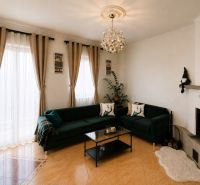 Wohnzimmer in einem Einfamilienhaus mit dunkelgrünem Sofa, Kamin und großen Fenstern.