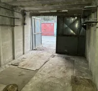 Betongarage mit offenen Stahltüren, Blick auf eine weitere Garage draußen.