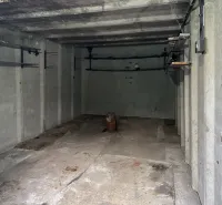 Betongarage in Bratislava - Nové Mesto mit einfachen Wänden und Lagerregalen.