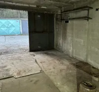 Innenraum einer Garage mit Betonboden und Metallregalen.