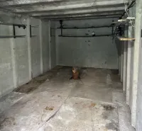 Innenraum einer Garage mit Betonwänden und Regalen zur Aufbewahrung von Gegenständen.