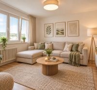 Wohnzimmer in einer Zweizimmerwohnung mit Sofa, Pflanzen und Holzboden.