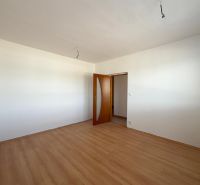 Ein Zimmer in einer 2-Zimmer-Wohnung mit einem Boden in Holzoptik und weißen Wänden.
