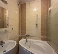 Badezimmer in einer 2-Zimmer-Wohnung mit Badewanne und Waschbecken, helle Fliesen.