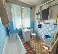 Ein Badezimmer in einem Einfamilienhaus mit blauen Fliesen, einer Badewanne und einem Waschbecken.