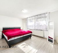 Schlafzimmer in einem Einfamilienhaus mit rotem Bett und Boden in Holzoptik.