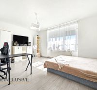 Helles Zimmer in einem Einfamilienhaus mit Bett, Tisch und Boden in Holzoptik.