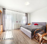 Ein Schlafzimmer in einem Einfamilienhaus mit einem Boden in Holzoptik, durchdacht angeordneten Möbeln und einem Schaukelstuhl.