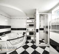 Ein Badezimmer in einem Einfamilienhaus mit Whirlpool, Dusche und schwarz-weißen Fliesen.