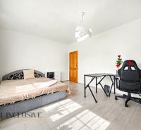 Ein Zimmer eines Einfamilienhauses mit einem Bett, einem Tisch und einem Stuhl auf einem Boden mit Holzdekor.