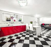 Helle Küche und Esszimmer im Einfamilienhaus mit schwarz-weißen Fliesen und roten Schränken.
