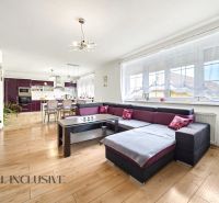 Wohnzimmer in einem Einfamilienhaus mit geräumigem Sofa und Boden in Holzoptik.