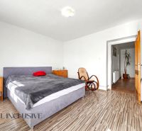 Ein Schlafzimmer in einem Einfamilienhaus mit einem bequemen Bett, einem Schaukelstuhl und einem Boden mit Holzdekor.