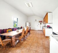 Eine geräumige Küche in einem Einfamilienhaus mit einer langen Essgruppe und Fliesenboden.