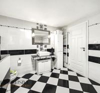 Ein Badezimmer in einem Einfamilienhaus mit schwarz-weißen Fliesen und einem Spiegel über dem Waschbecken.