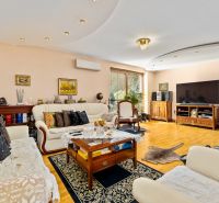 Helles Wohnzimmer in einem Einfamilienhaus mit bequemen Sitzgelegenheiten und einem Boden in Holzoptik.
