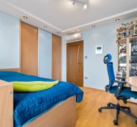 Schlafzimmer in einem Einfamilienhaus mit Schrank, blauem Bett, Trophäen und Holzboden.