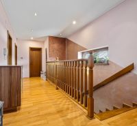 Flur mit Treppe in einem Einfamilienhaus, Boden mit Holzdekor, Spiegel und Pflanzen.