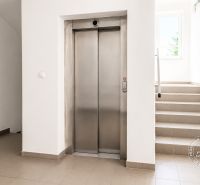 Flur mit Aufzug und Treppe, die zu einem Fenster führen, 2-Zimmer-Wohnung.