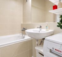 Badezimmer in einer 2-Zimmer-Wohnung mit Badewanne, Waschbecken und Waschmaschine.