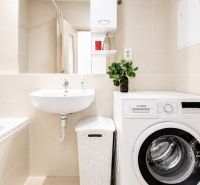 Badezimmer in einer 2-Zimmer-Wohnung mit Badewanne, Waschmaschine und Waschbecken.