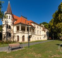 Historisches Gebäude in Stupava in der Vincenta Šikulu-Straße, umgeben von Grünflächen und einem Gehweg.