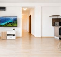 Wohnbereich einer 2-Zimmer-Wohnung mit Holzboden und einem Fernseher an der Wand.