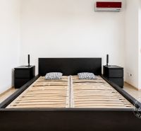 Schlafzimmer in einer 2-Zimmer-Wohnung mit einem Bett und Nachttischen in schwarzer Farbe.