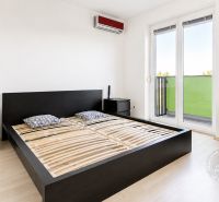 Schlafzimmer in einer 2-Zimmer-Wohnung mit Bett, Kommode und Boden in Holzoptik.