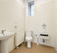 Toilette in Büros mit beigen Fliesen und Waschbecken.