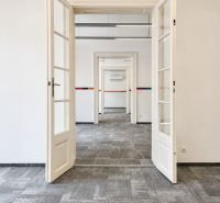 Eine offene weiße Tür in einem Büro mit Teppichboden.
