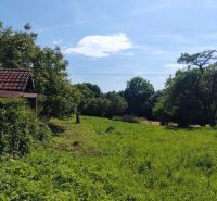 Grüne Wohnbaugrundstücke in Žehňa, umgeben von Bäumen und blauem Himmel.