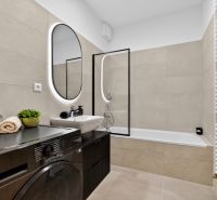 Badezimmer mit Badewanne, Waschmaschine und Spiegel in einer Zweizimmerwohnung.