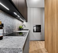Küche in einer 2-Zimmer-Wohnung mit grauer Arbeitsplatte und Boden in Holzoptik.