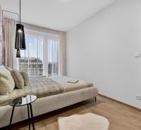 Schlafzimmer mit hellen Möbeln, Boden in Holzoptik, großem Fenster und Vorhang.