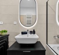 Badezimmer in einer 2-Zimmer-Wohnung mit Waschbecken, Spiegel und Badewanne. Accessoires in schwarzer Farbe.