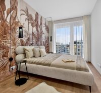 Schlafzimmer in einer 2-Zimmer-Wohnung mit tropischer Tapete und Holzboden.