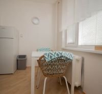 Küche in einer Einzimmerwohnung mit Holzboden, Tisch und Stühlen.