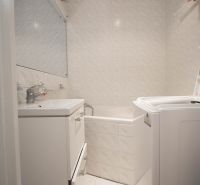 Badezimmer mit Badewanne, Waschbecken und Waschmaschine in einer Einzimmerwohnung.