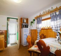 Das Innere der Hütte mit Holzelementen, traditionellem Mobiliar und einem dekorierten Fenster.